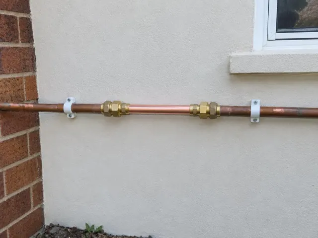Repaired copper water pipe on an exterior brick and rendered wall in Collaroy
