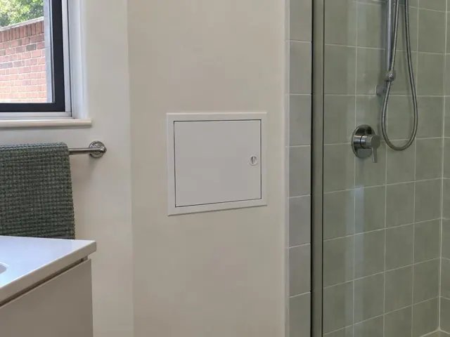 Small wall access panel beside a tiled shower in a modern bathroom in Beacon Hill